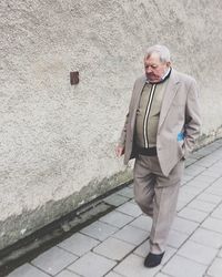 Man walking on footpath against wall