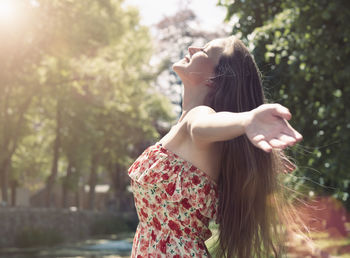 Young woman standing against trees