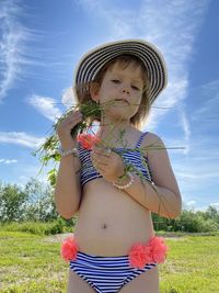 Girl wearing hat standing on field against sky