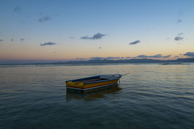 Boat in sea against sky during sunset