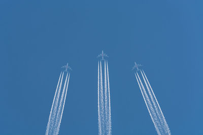 Low angle view of airplane flying against clear blue sky