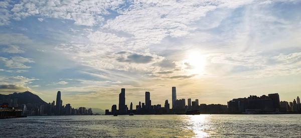 Sea by buildings against sky during sunset