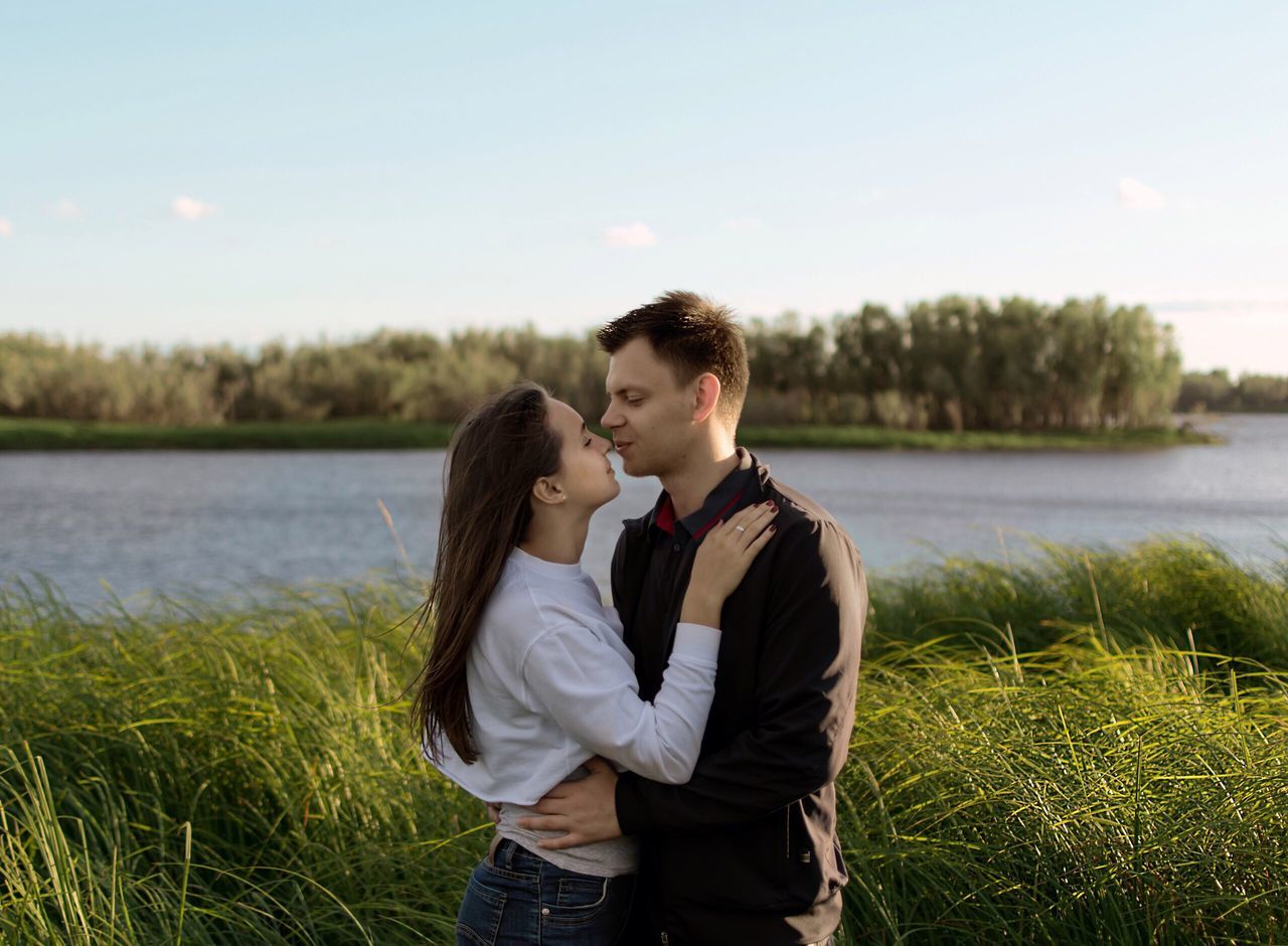 love, togetherness, romance, grass, two people, affectionate, young adult, lake, couple - relationship, happiness, men, child, water, civil partnership, smiling, nature, bonding, people, outdoors, adult, sky, day