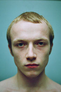 Close-up portrait of young man against blue background