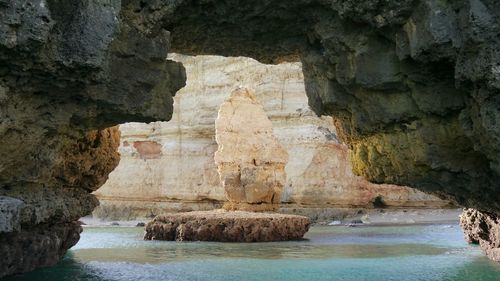 Rock formation in sea behind cave