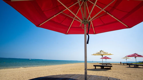 Deck chairs and parasols on beach against clear sky