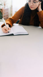 Midsection of woman reading book against white background