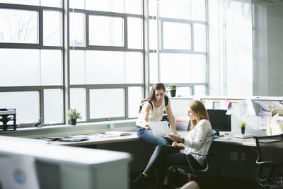 Female colleagues analyzing data at desk in office