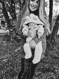 Full length of a girl holding tree trunk