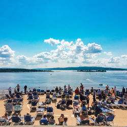 People at observation point by sea against sky