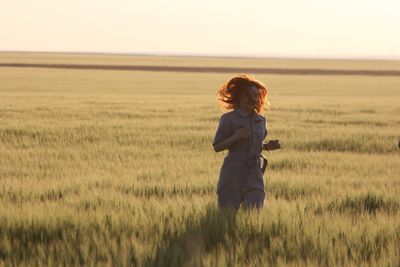 Woman running on grassy field during sunset