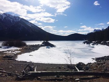 Scenic view of lake by snowcapped mountains against sky