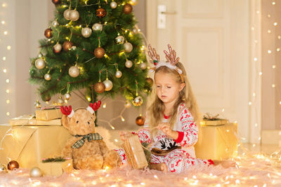 Cute girl holding christmas gift at home