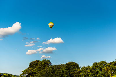 Low angle view of hot air balloon flying against blue sky