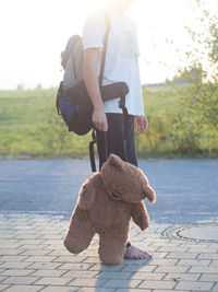 Low section of man holding teddy bear on footpath
