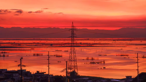 Silhouette electricity pylon against dramatic sky during sunrise