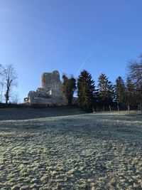 Built structure on field against clear blue sky