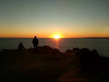 Silhouette people at beach against sky during sunset