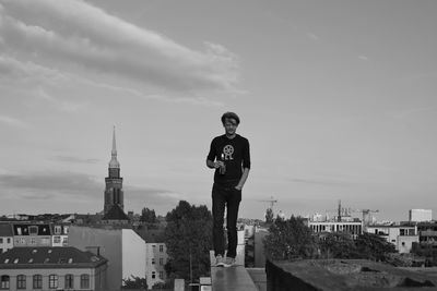 Man standing by building against sky in city