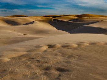 Sand dunes in desert against sky