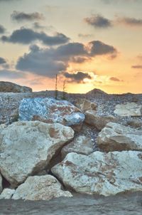 Rocks on beach against sky during sunset