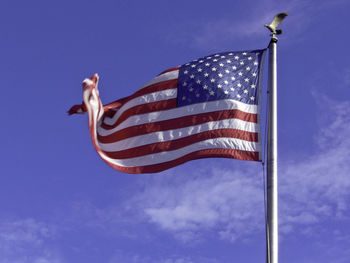 Low angle view of flag flying against blue sky