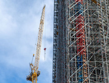 Low angle view of crane at construction site against sky