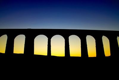 Low angle view of silhouette built structure against blue sky