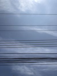 Low angle view of power cables against sky