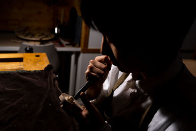 Young chinese female violin maker working with gouge to making a new violin in her workshop