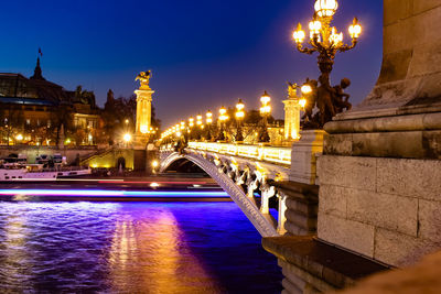 Illuminated bridge over river at night