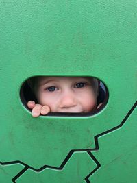 Portrait of boy peeking through hole