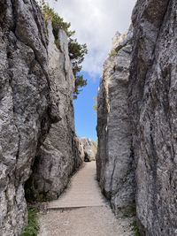 Footpath amidst rocks against sky