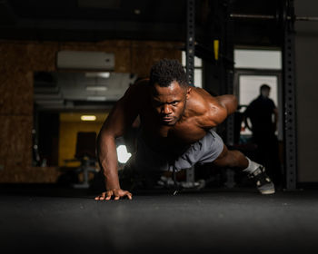 African american man doing one arm push ups in the gym