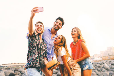 Smiling friends taking selfie while standing outdoors
