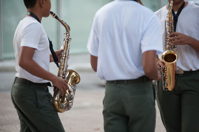 Midsection of street musicians plying saxophone