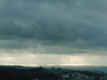 Buildings in city against storm clouds