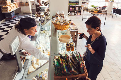 High angle view of woman buying grocery from saleswoman at store