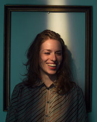 Portrait of smiling young woman standing against wall