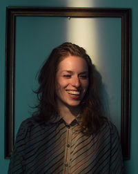 Mid adult woman standing against picture frame on wall