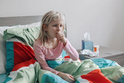 Full length of girl sitting on bed