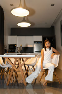 Young woman sitting on chair at kitchen 