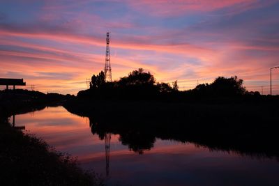 Silhouette trees by lake against sky during sunset