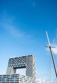 Low angle view of building and mast against blue sky