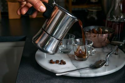 Man preparing classic italian coffee in the mocha. pouring coffee from moka pot to small coffee cup.