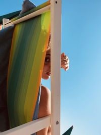 Low angle view portrait of woman sitting on lounge chair against sky