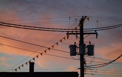 Low angle view of silhouette electricity pylon against sky during sunset