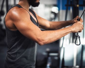 Midsection of young man exercising in gym