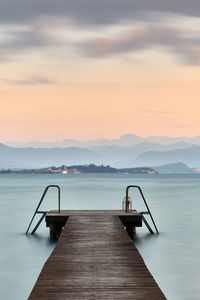 Pier on swimming pool against sky during sunset