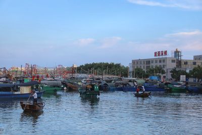 Sailboats moored on river by buildings in city against sky